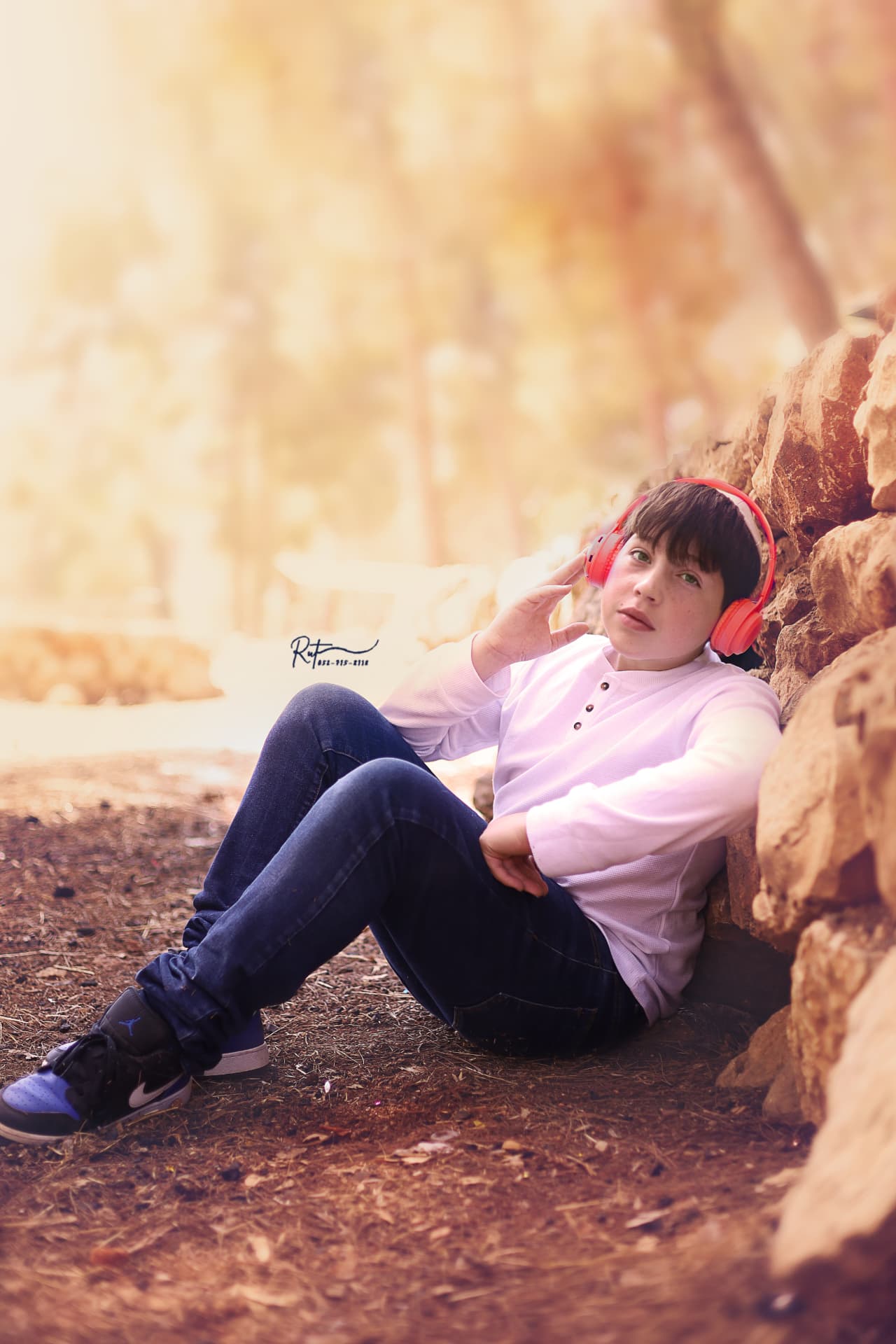 ילד עם אוזניות אדומות נשען על סלעים