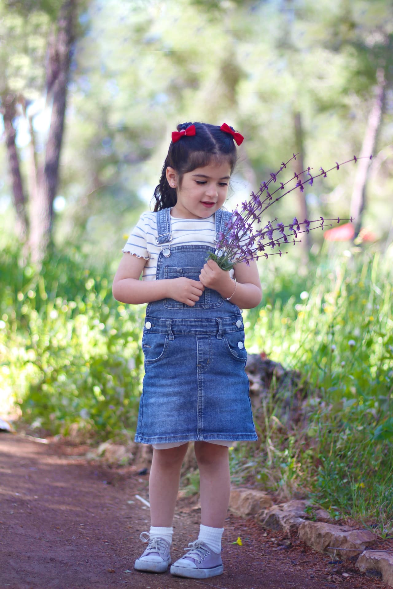 ילדה עם סינר ג'ינס אוחזת בפרחי בר
