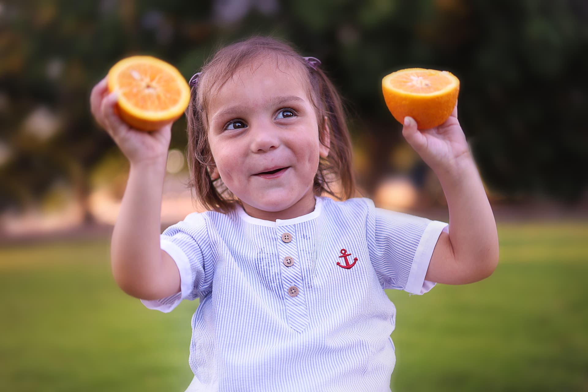 ילדה מרימה שתי חצאי תפוזים